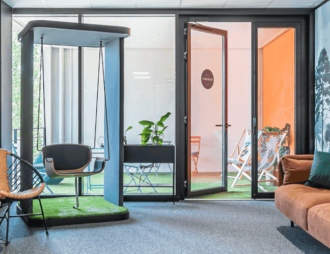 Espace détente et coworking de B'CoWorker Schiltigheim avec canapé, fauteuils, balançoire intérieure et accès à une terrasse.