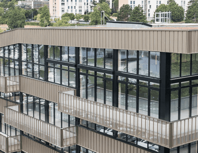 Vue en hauteur du bâtiment Le Phénix à Laxou, montrant l’angle vitré, les façades et les abords routiers, BMG Foncière.
