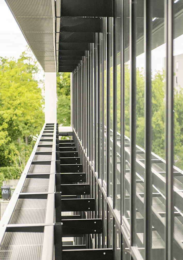 Vue d’une façade vitrée du Bridge à Mérignac, avec une ambiance intérieure verte visible derrière les vitrages, BMG Foncière.