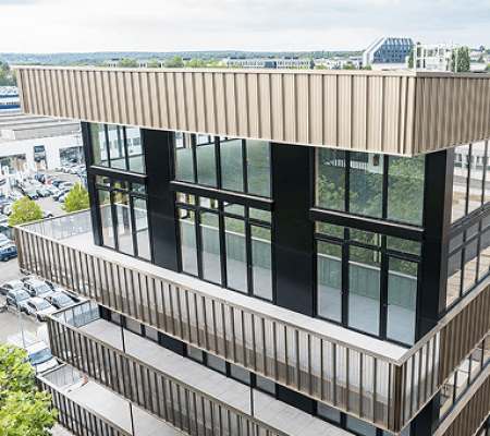 Vue rapprochée de l’angle vitré du bâtiment Le Phénix à Laxou, avec façade claire et niveaux de bureaux, BMG Foncière.